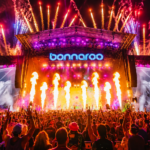 The Bonnaroo main stage lights up with fireworks, flames, and lasers over a massive crowd at night, as the festival announces it will take 2027 off.