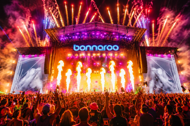 The Bonnaroo main stage lights up with fireworks, flames, and lasers over a massive crowd at night, as the festival announces it will take 2027 off.