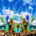 Boomtown's elaborate main stage erupts with fireworks and flames over a packed crowd, from the festival Luke Mitchell built.