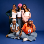 The five members of Cuzzos, the all-female South Central LA rap group, pose together against a blue backdrop in casual streetwear, in press art for their single 'Can't Pretend.'