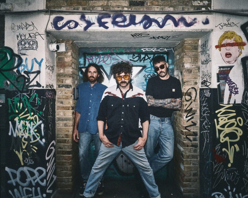 London trio Dead Horse pose in a graffiti-covered doorway, promoting their single 'I Would Die' from debut album 'Caught The Nonsense.'