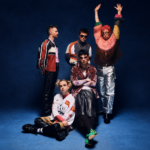 Fontaines D.C., who debuted new songs 'Marianne' and 'Six Shot Morning' live, pose against a deep blue backdrop in a press photo.