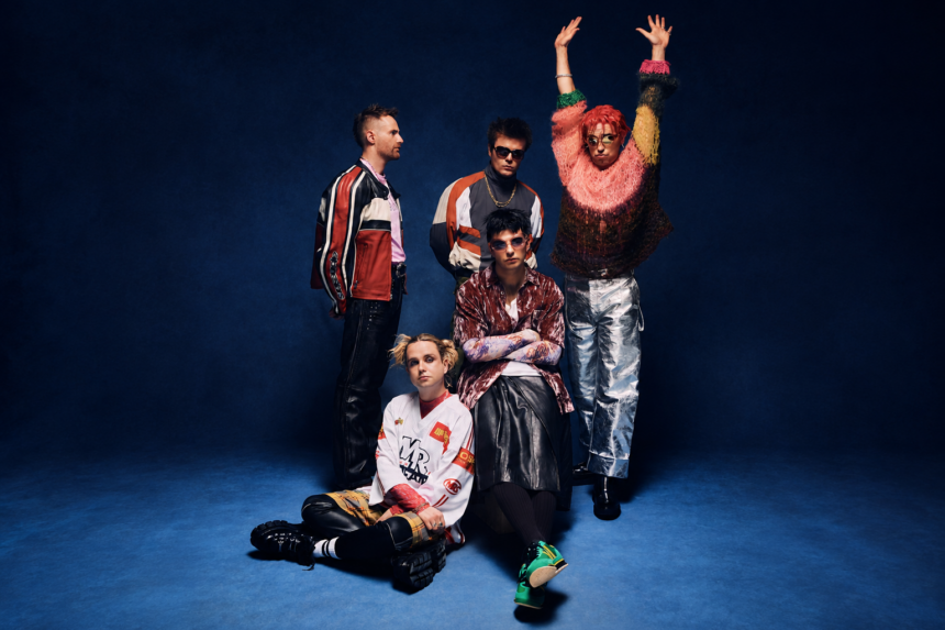 Fontaines D.C., who debuted new songs 'Marianne' and 'Six Shot Morning' live, pose against a deep blue backdrop in a press photo.