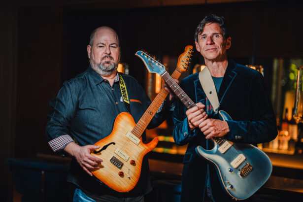 The two members of Heavy Set Woman, Gumpi Falcon and William "Willo" Serrallés, pose holding electric guitars in a warmly lit bar setting, promoting their single "Girl."