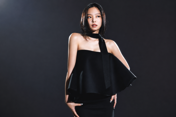 BLACKPINK's Jennie poses in an elegant black one-shoulder dress against a dark backdrop in a photo shoot, around the announcement of her solo EP 'Fallen Angel.'