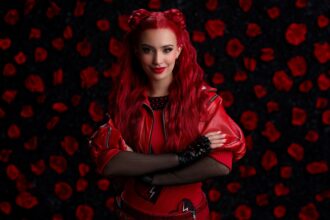 Kylie Cantrall poses with vibrant red hair styled in space buns, wearing a red leather jacket