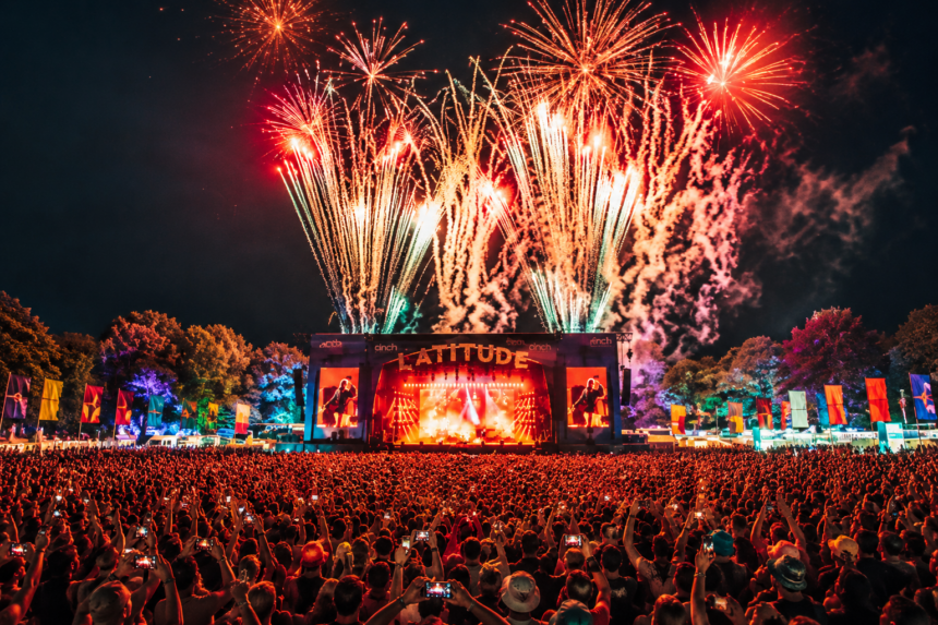 Fireworks erupt over the main stage at Latitude Festival's Henham Park as a massive crowd holds up phones during a headline set at night.