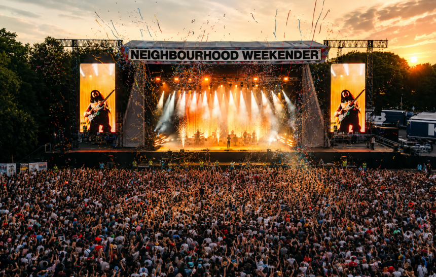 A huge crowd fills Victoria Park in front of the main stage at dusk during Neighbourhood Weekender, tied to the festival's 2027 lineup announcement.
