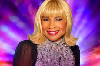 Disco icon Norma Jean Wright smiles in a sparkling silver top against a vibrant purple and pink backdrop, promoting her single 'Ode To Disco.'