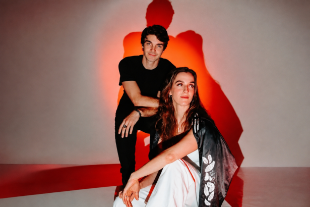Reality Distortion, whose debut EP 'Ceasefire' is out now, pose against a red-lit backdrop in a moody sibling-duo portrait.