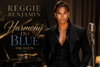 Album cover for Reggie Benjamin's 'Harmony In Blue: The Duets,' showing Benjamin in a black suit beside a grand piano and vintage microphone, featuring Lisa Vanderpump, Joe Mantegna and more.
