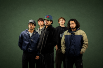 Perth band South Summit, whose album 'Run It Back' is out now, pose against a dark green backdrop in a moody press photo.