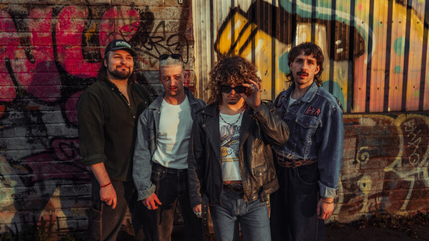 The four members of Bristol band Spin Class pose in denim and leather against a graffiti-covered wall at golden hour, in press art for their single 'Rip 'N' Dip.'