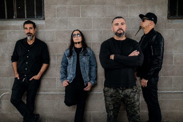 The four members of System of a Down lean against a grey cinderblock wall in dark clothing, promoting their one-night-only Maracanã Stadium concert in Rio de Janeiro.