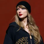 Taylor Swift walks through a desert at sunset in a flowing peach dress with pink-tipped hair, in press-style art tied to her Radio Songs No. 1 'I Knew It, I Knew You.'