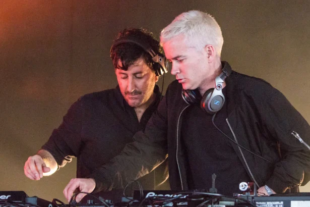 The Avalanches, who have announced their album 'No Bad Memories,' perform a DJ set behind Pioneer decks under warm stage lights.