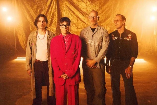 Weezer, whose single 'C.E.O.' precedes The Gold Album, pose against a gold backdrop with Rivers Cuomo in a red suit at center.