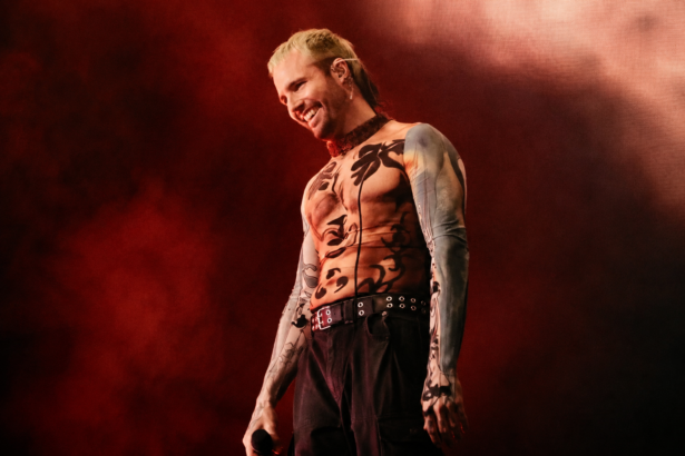 What So Not performs live against a red-lit backdrop, smiling with a mic in hand and wearing a patterned mesh top, in press-style art tied to his new project and tour.