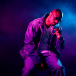 Chicago rapper Don Che posing in a denim jacket and chain under pink and blue studio lighting