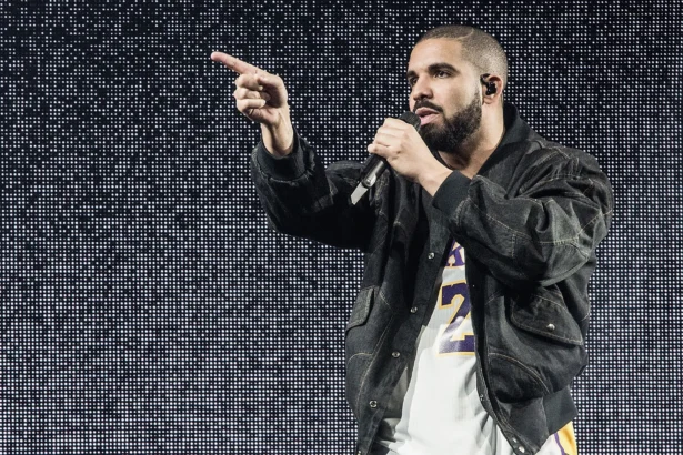 Drake performs onstage with a mic, pointing to the crowd in a denim jacket and Lakers jersey against an LED backdrop, tied to his surprise 'ICEMAN' set at Don Toliver's Toronto show.