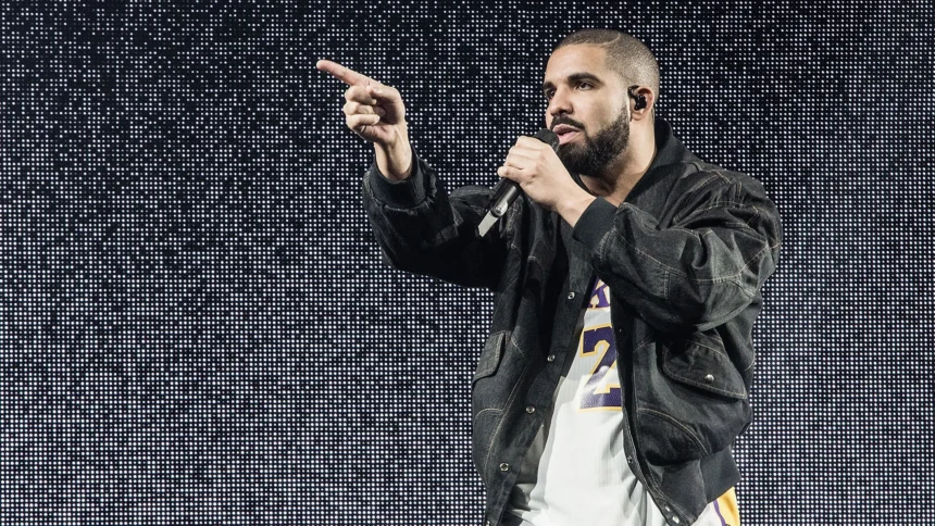 Drake performs onstage with a mic, pointing to the crowd in a denim jacket and Lakers jersey against an LED backdrop, tied to his surprise 'ICEMAN' set at Don Toliver's Toronto show.
