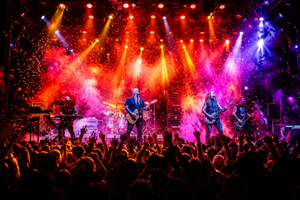 Neurosis perform onstage under red and blue lighting before a silhouetted crowd at Fire in the Mountains 2026, tied to the festival's 2027 lineup announcement.
