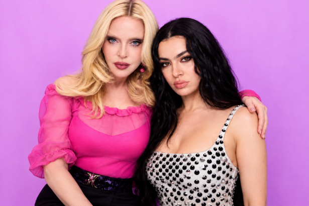Madonna and Charli xcx posing together against a pink backdrop, one in a pink blouse and one in a studded silver top