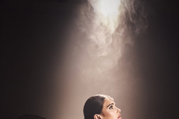Mila Sidhu in profile wearing a black lehenga, maang tikka and chandbali earrings under a beam of light