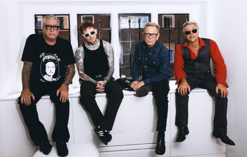 The Sex Pistols with frontman Frank Carter sit together by a window in a press photo, tied to their 2026 '50 Years of Punk' UK tour.