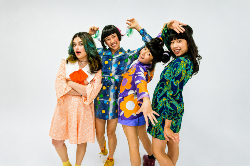 The four members of The Linda Lindas strike playful poses in colorful retro-print outfits against a white backdrop, in press art for their album 'Gotta Get Out.'