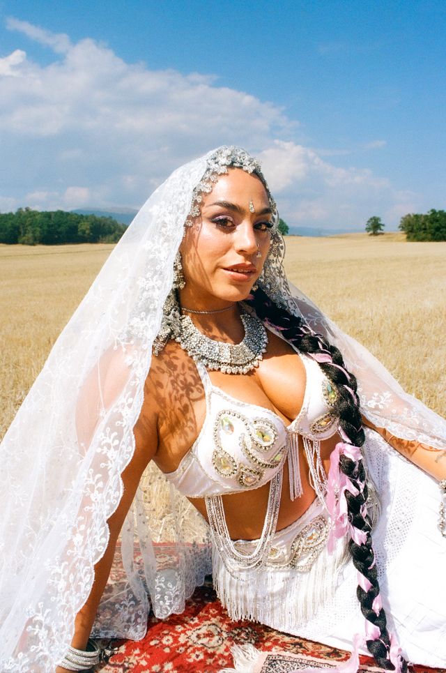 BombayMami in an embellished white bridal look and lace veil in a wheat field, promoting ‘Honey Liquor.’