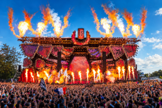 Ultra Music Festival 2027 promotional poster showing the main stage framed by jets of flame above a packed crowd, with “Tickets On Sale Now” and the dates March 26, 27, 28, 2027 at Bayfront Park, Miami.